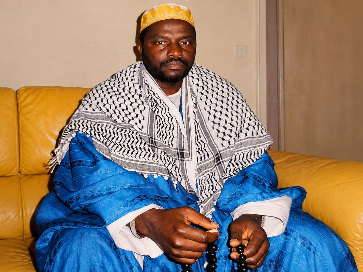 Maître Hady en boubou bleu et keffieh, chapelet de prière entre les mains